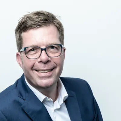 Dr. Andreas Tietz - Gründer orgalean GmbH: Ein Mann mit Brille lächelt in die Kamera.