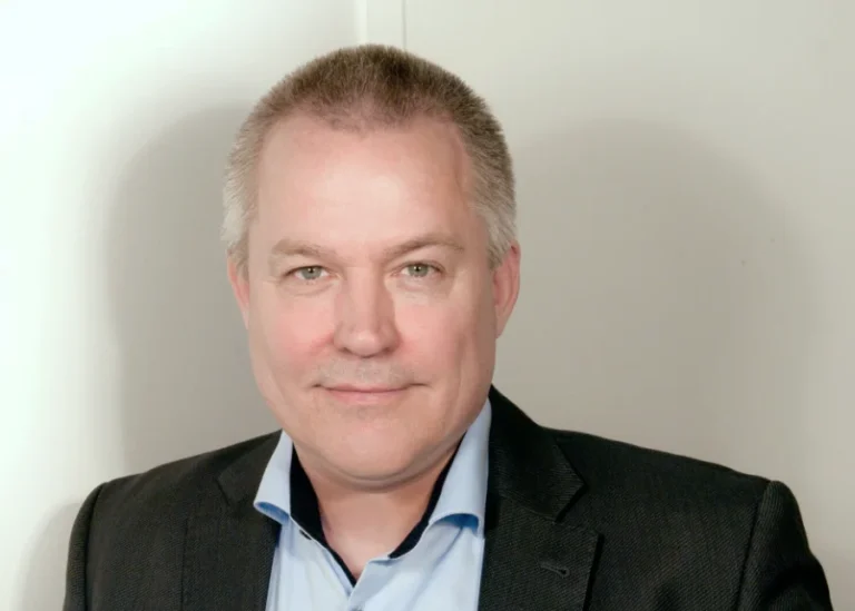 Profilbild von Arndt Cornelsen: Ein Mann mit kurzen Haaren schmunzelt in die Kamera.